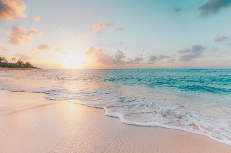 Deserted tropical beach at sunsetwith gentle waves lapping at the sand.