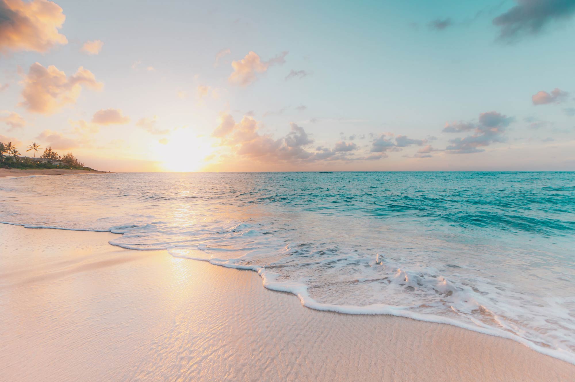 Deserted tropical beach at sunsetwith gentle waves lapping at the sand.